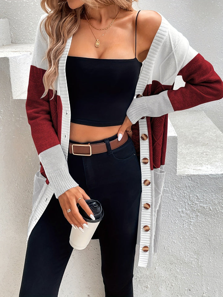 Frau in langem, gestreiftem Cardigan, schwarz-rotes Design, hält Kaffeebecher, modisch, lässig.