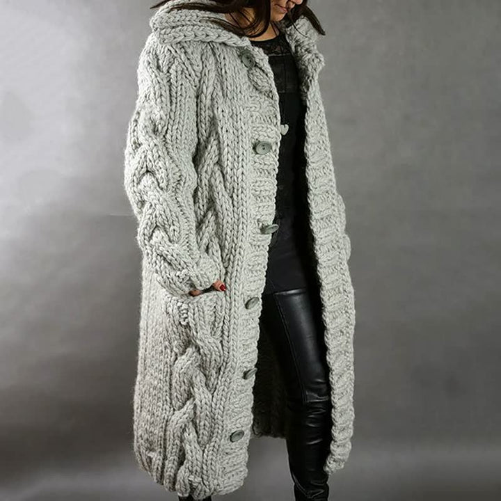 Frau in grauem, grob gestricktem Wollmantel mit Zopfmuster, modisch, warm, Winterkleidung.