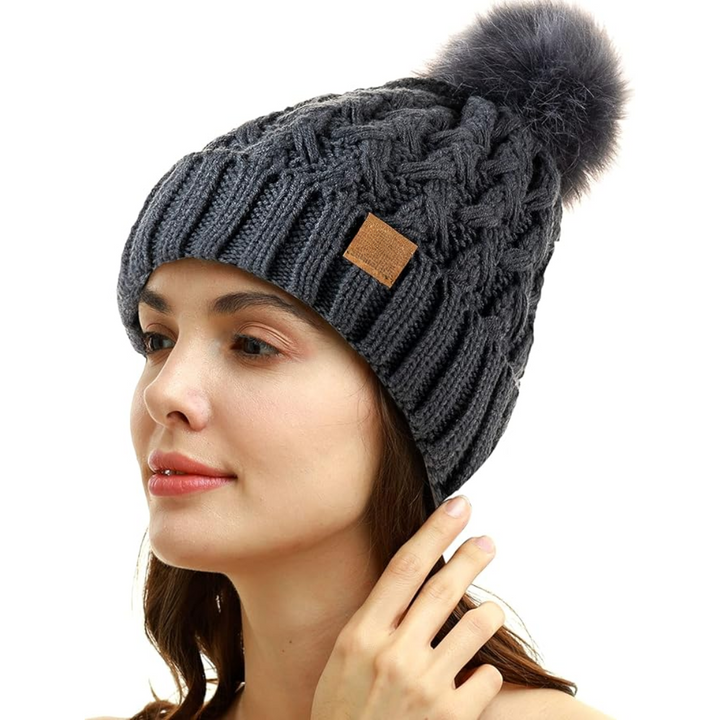 Frau mit grauer Strickmütze, Bommel, Wintermode, warm, stilvoll, Accessoire, Damenbekleidung.