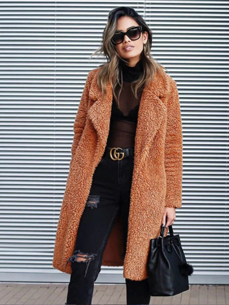 Frau in braunem Teddy-Mantel, schwarze Sonnenbrille, zerrissene Jeans, schwarze Handtasche.