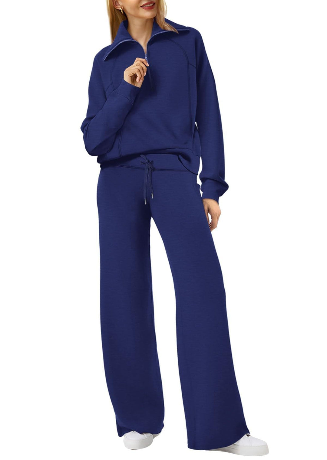 Frau in dunkelblauem Jogginganzug mit weitem Bein, Reißverschluss und Kordelzug, sportlich elegant.