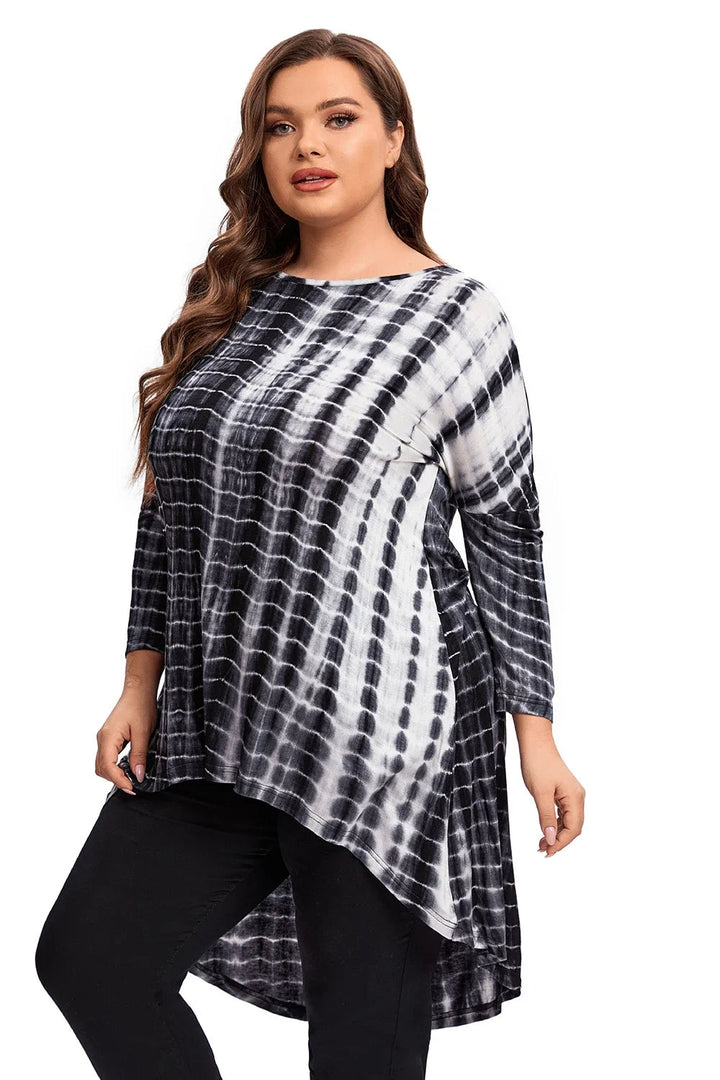 Frau in schwarz-weißem Batik-Oberteil, asymmetrischer Schnitt, lange Ärmel, Plus-Size-Mode.