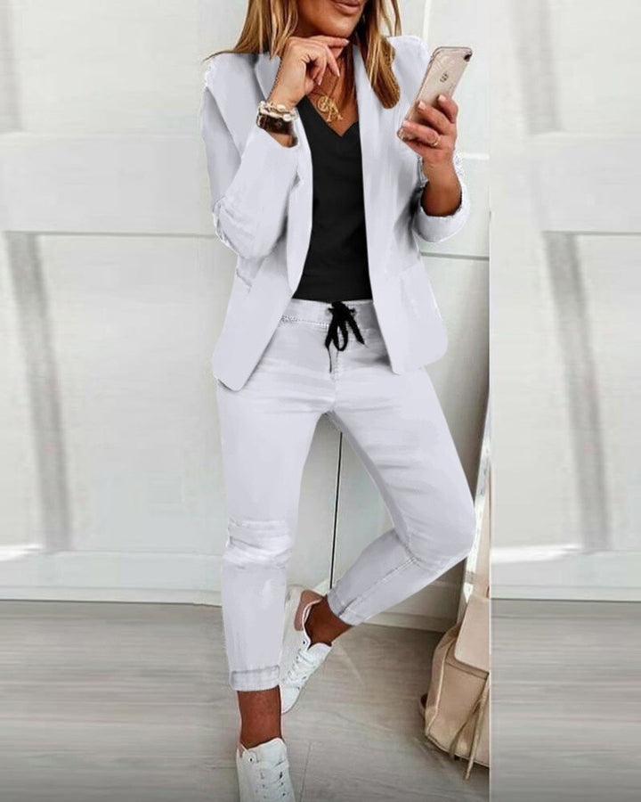 Frau in weißem Anzug mit Smartphone, schwarze Bluse, lässiger Look, Mode für Damen.