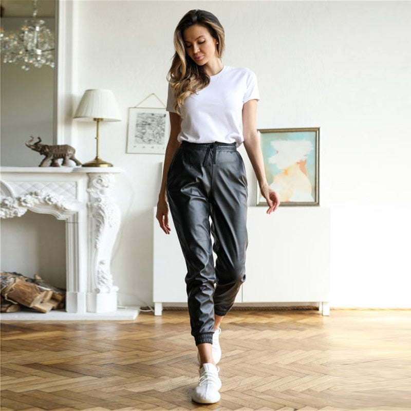 Frau in weißem T-Shirt und schwarzer Lederhose, lässig, modern, stilvoll, Wohnzimmer.