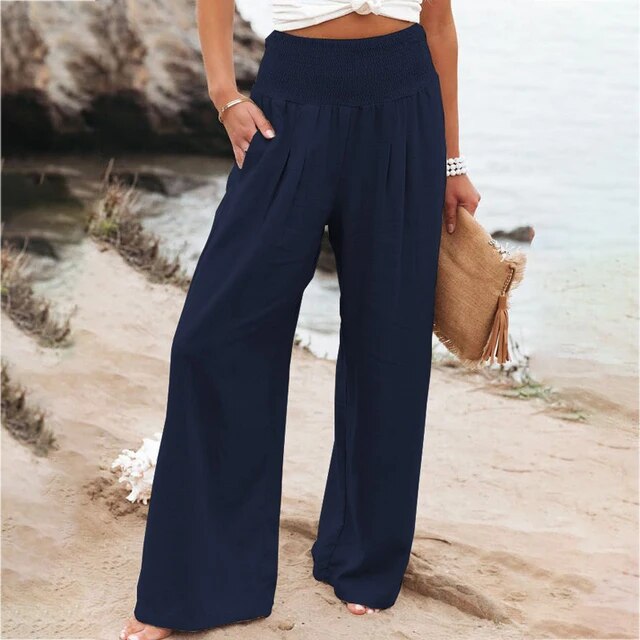 Frau in blauer, weiter Hose am Strand, Sommermode, lässiger Stil, Damenbekleidung.
