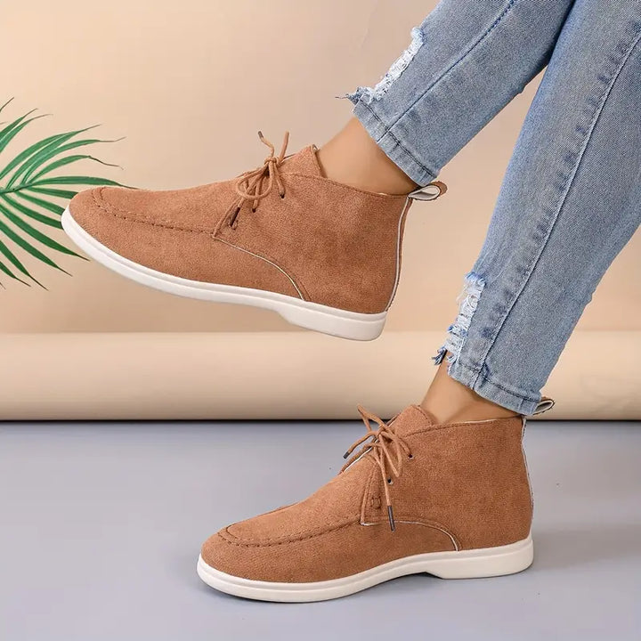 Damen Stiefeletten aus Wildleder in Braun, lässig, mit Schnürung, kombiniert mit zerrissenen Jeans.