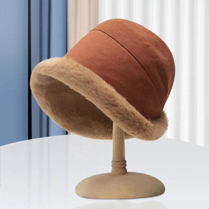 Brauner Damenhut mit Kunstfellrand auf Holzständer, modisch, elegant, Herbst-Winter-Accessoire.