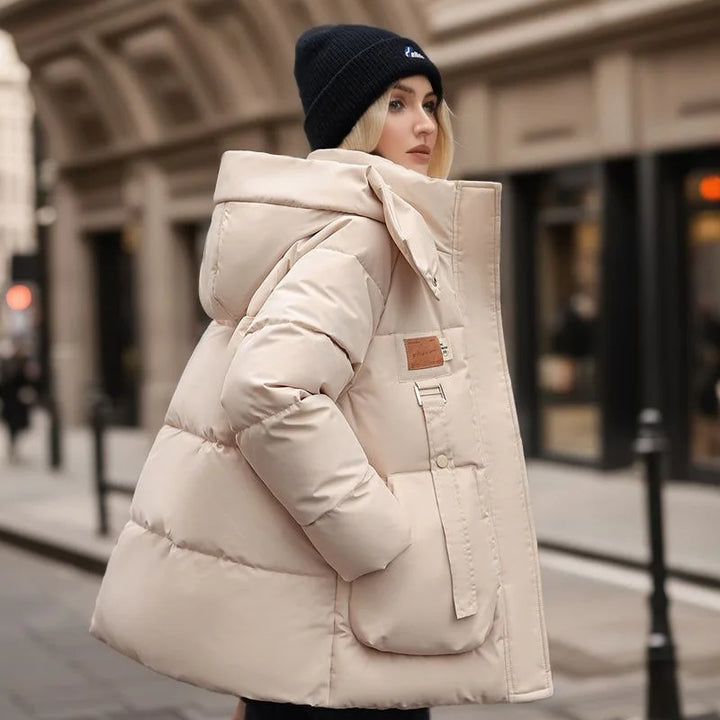 Frau in beiger Winterjacke mit Kapuze, warm, winddicht, modisch, auf städtischer Straße.