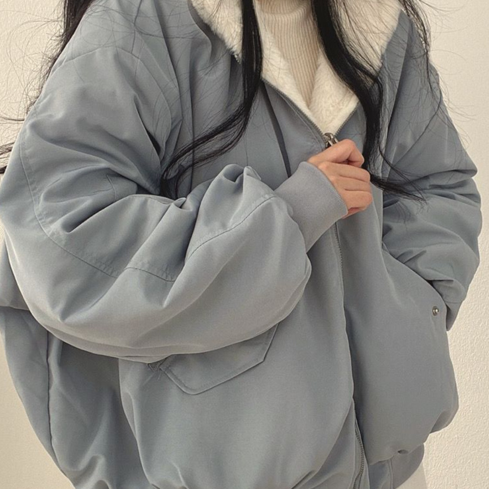 Frau in hellblauer Winterjacke mit weißem Futter, Reißverschluss, modisch, warm, Damenbekleidung.