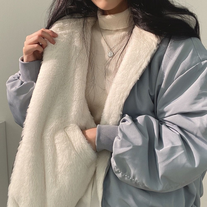 Frau in blauer Jacke mit weißem Kunstfell, Rollkragenpullover, Wintermode, elegant.