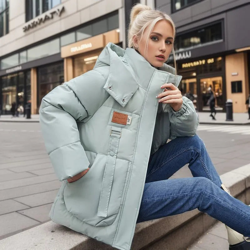 Frau in mintgrüner Winterjacke, Daunenoptik, Kapuze, warm, winddicht, modisch, Stadtumgebung.