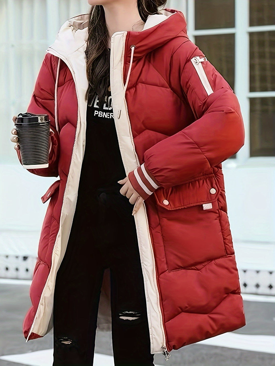 Frau in roter Daunenjacke mit Kapuze, hält schwarzen Becher, Wintermode, Outdoor-Bekleidung.