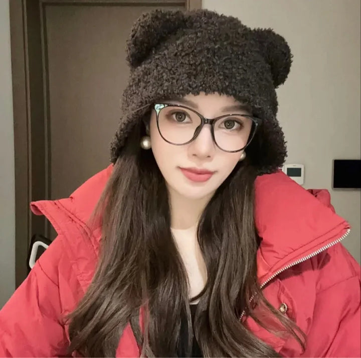 Frau mit schwarzem Teddyfell-Hut, Brille und roter Jacke, Wintermode Accessoire.