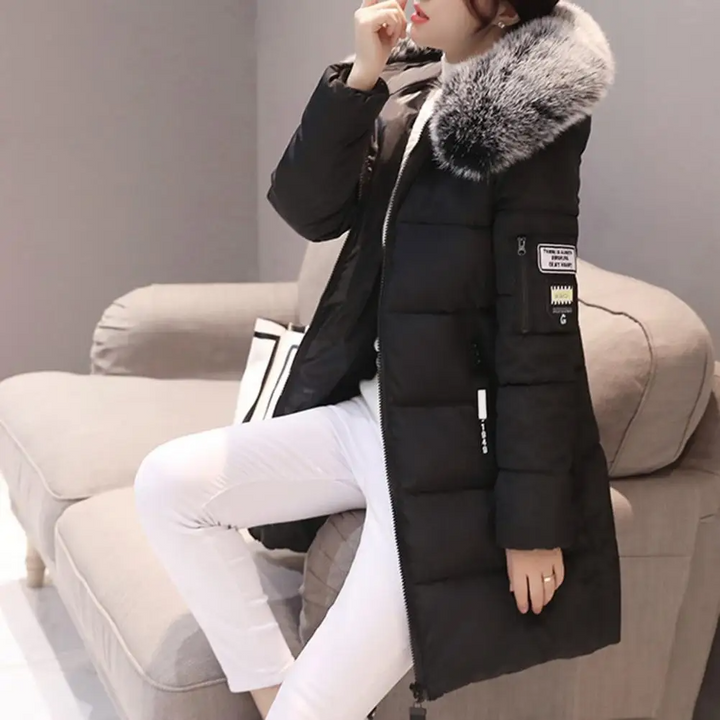 Frau in schwarzem Daunenmantel mit Fellkapuze, sitzt auf Sofa, Wintermode, elegant, warm.