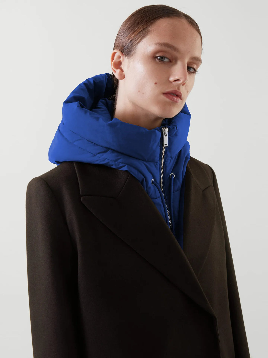 Frau in schwarzem Mantel mit blauem Kapuzenpullover, modisch, elegant, Winterkleidung.