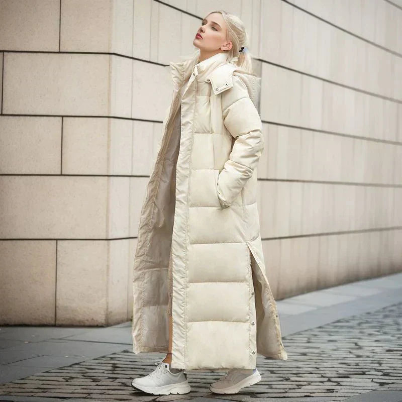 Frau in langem, beigem Daunenmantel, Wintermode, urbaner Hintergrund, stilvolle Kleidung.