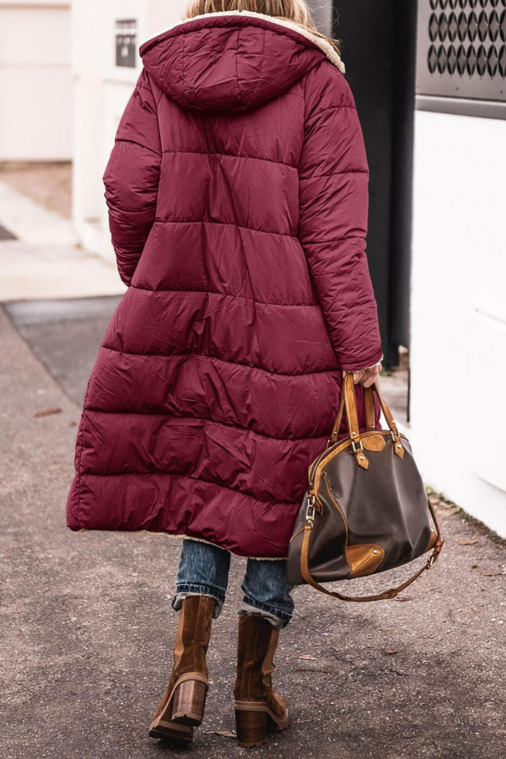 Frau in rotem Daunenmantel mit Kapuze, braune Lederstiefel, braune Handtasche, Straße.