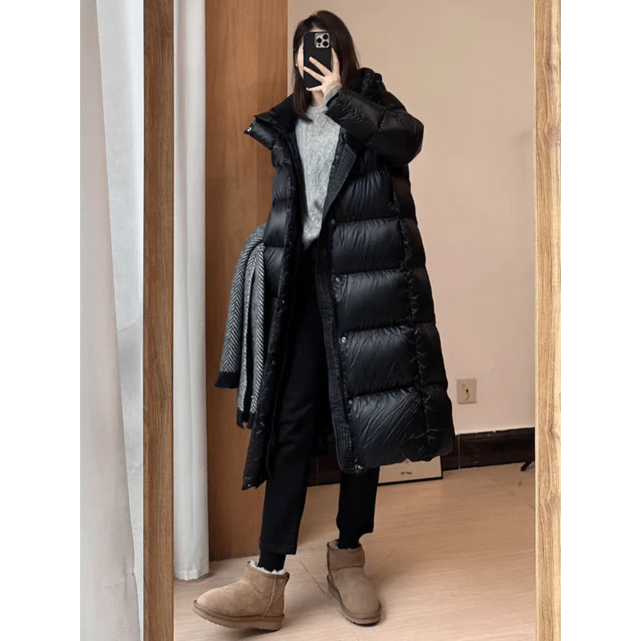 Frau in schwarzem Daunenmantel, grauem Pullover, schwarzer Hose, braunen Stiefeln, Spiegel-Selfie.