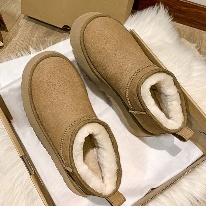 Braune Damen-Winterstiefel aus Wildleder mit weißem Futter in Schuhkarton auf Holzboden.