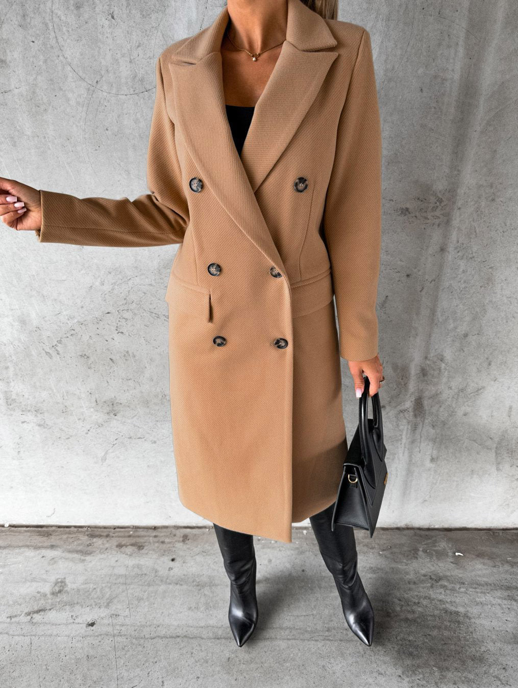 Eleganter Damenmantel, beige, doppelreihig, Herbstmode, stilvoll, mit schwarzer Handtasche.