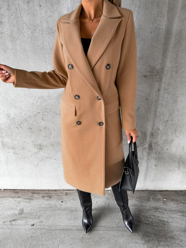 Eleganter Damenmantel, beige, doppelreihig, Herbstmode, stilvoll, mit schwarzer Handtasche.