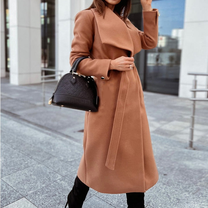 Frau in braunem Wollmantel mit schwarzer Handtasche, eleganter Herbstlook, Stadtumgebung.