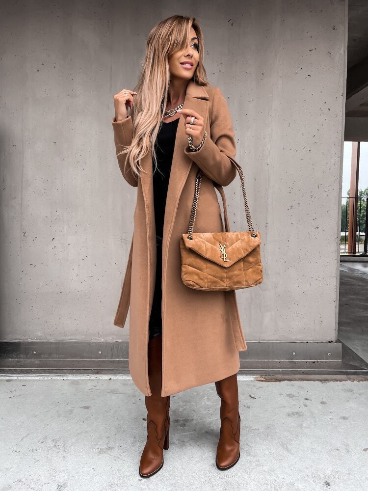 Frau in braunem Mantel, braunen Stiefeln, mit brauner Handtasche, modisch, urbaner Hintergrund.