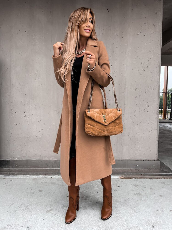 Frau in braunem Mantel, braunen Stiefeln, mit brauner Handtasche, modisch, urbaner Hintergrund.