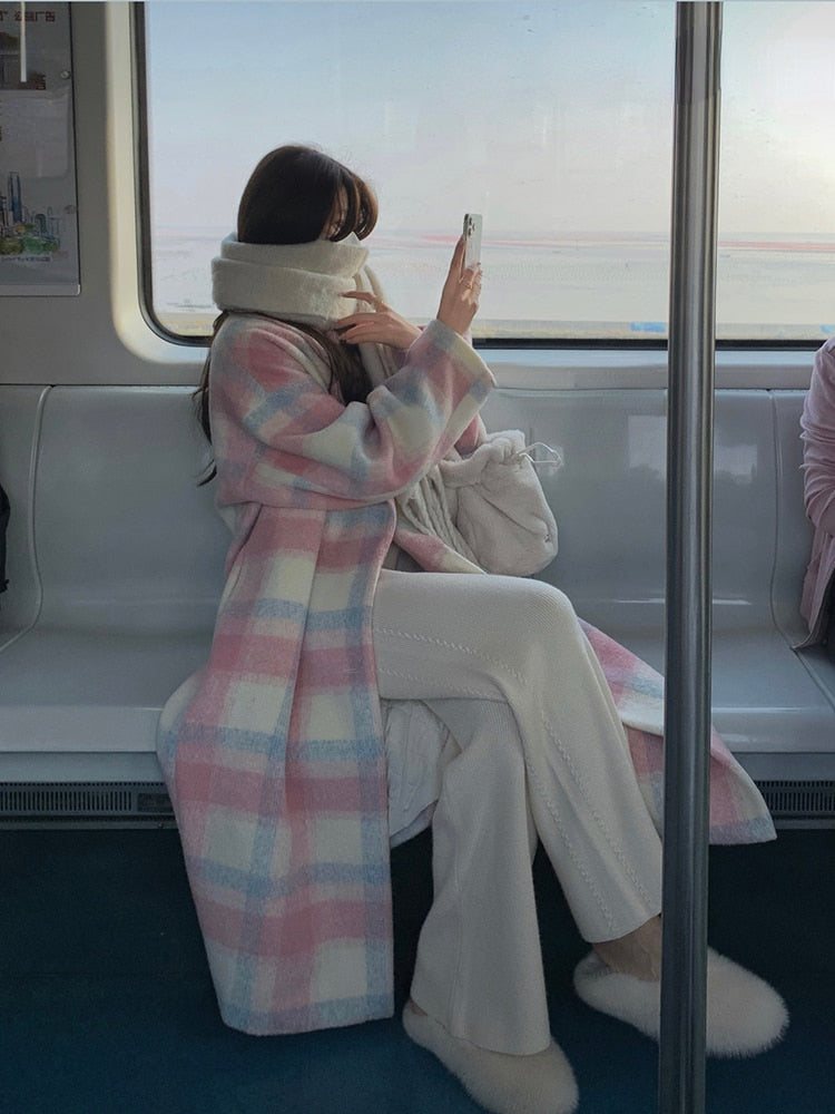 Frau im Zug mit kariertem Mantel, Smartphone, Wintermode, pastellfarben, gemütlich, modern.