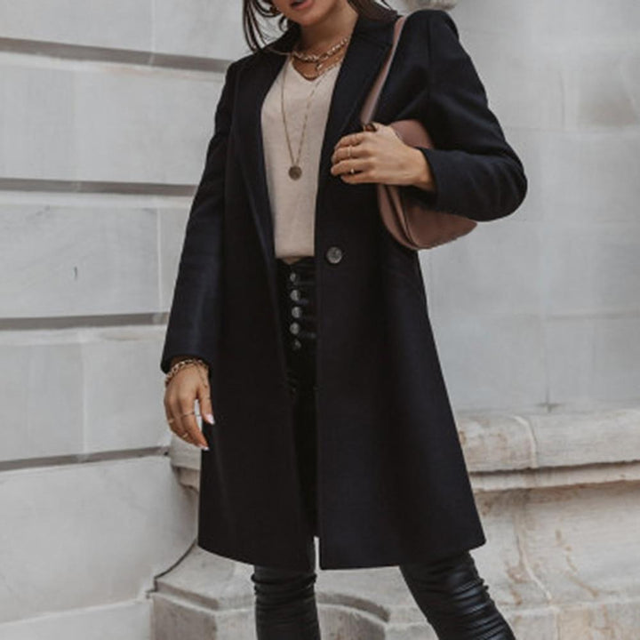 Schwarzer Damenmantel, elegant, knielang, Herbstmode, kombiniert mit beiger Bluse und Lederhose.