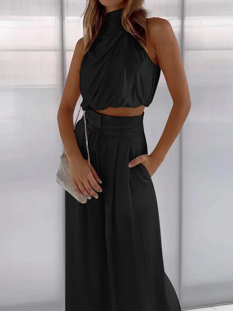 Frau in schwarzem, ärmellosem Seiden-Zweiteiler mit weitem Bein, elegantes Outfit.