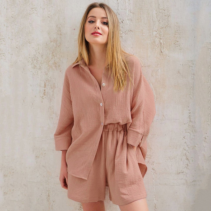 Frau in rosa Leinen-Set, bestehend aus Hemd und Shorts, vor beiger Wand.