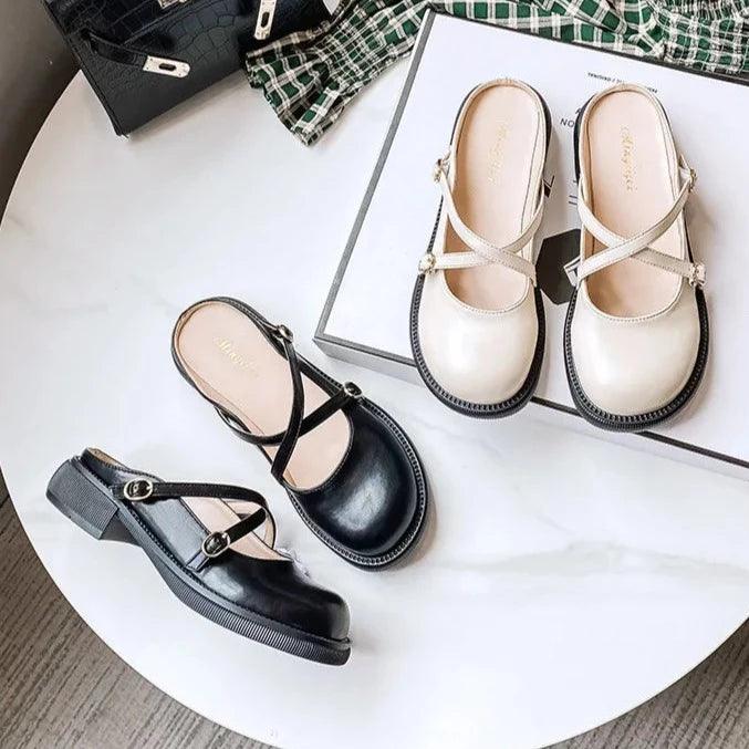 Schwarze und weiße Damenlederhalbschuhe mit Riemen auf Marmortisch, modisch und bequem.