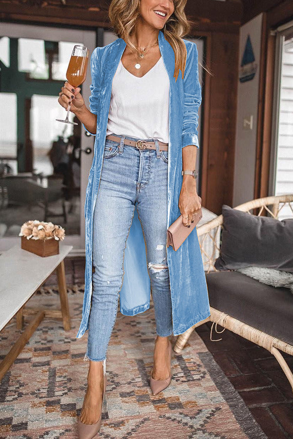 Frau in hellblauem Cardigan, Jeans, weißem Top, hält Weinglas, modisch, lässiger Stil.
