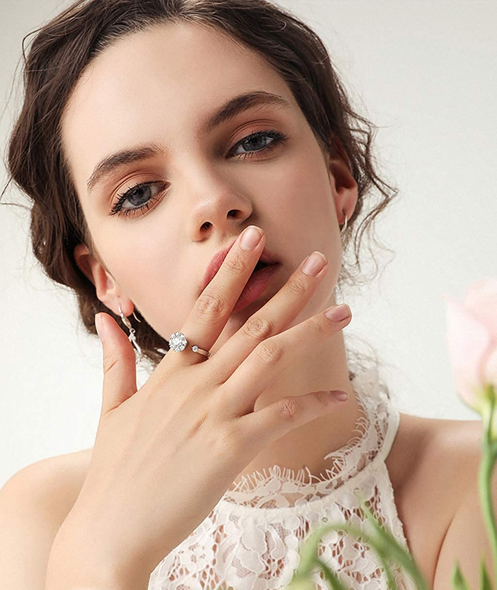 Dame mit weißem Spitzenkleid trägt eleganten Silberring mit großem Diamant, Nahaufnahme.