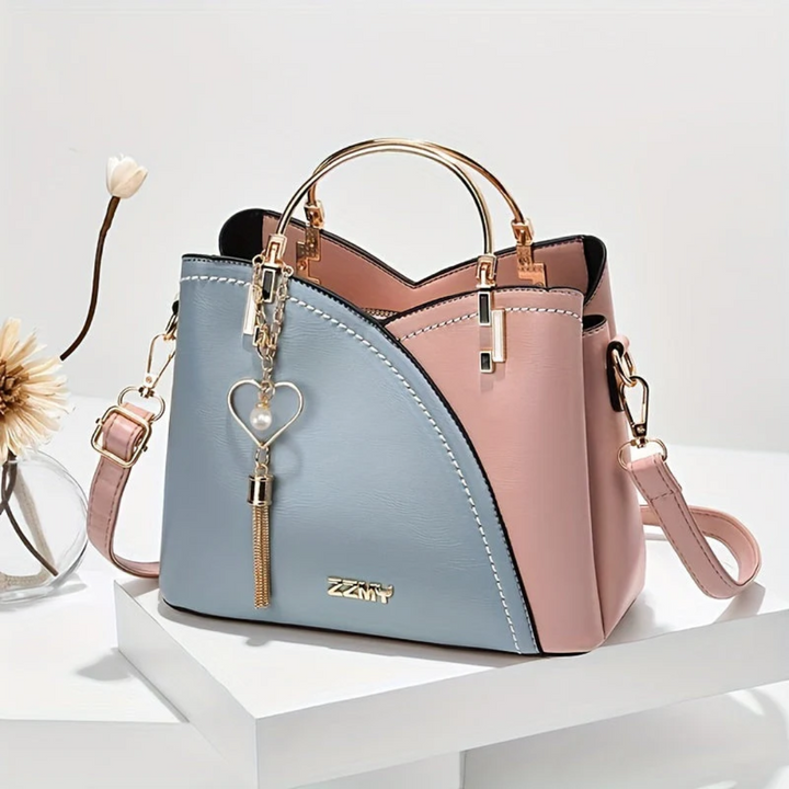 Damenhandtasche aus Leder, zweifarbig rosa-blau, mit Herzanhänger, elegantes Design.