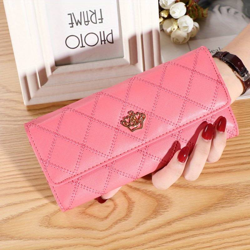 Damen Geldbörse rosa Leder, gesteppt, elegant, mit Metall-Logo, auf Holztisch.