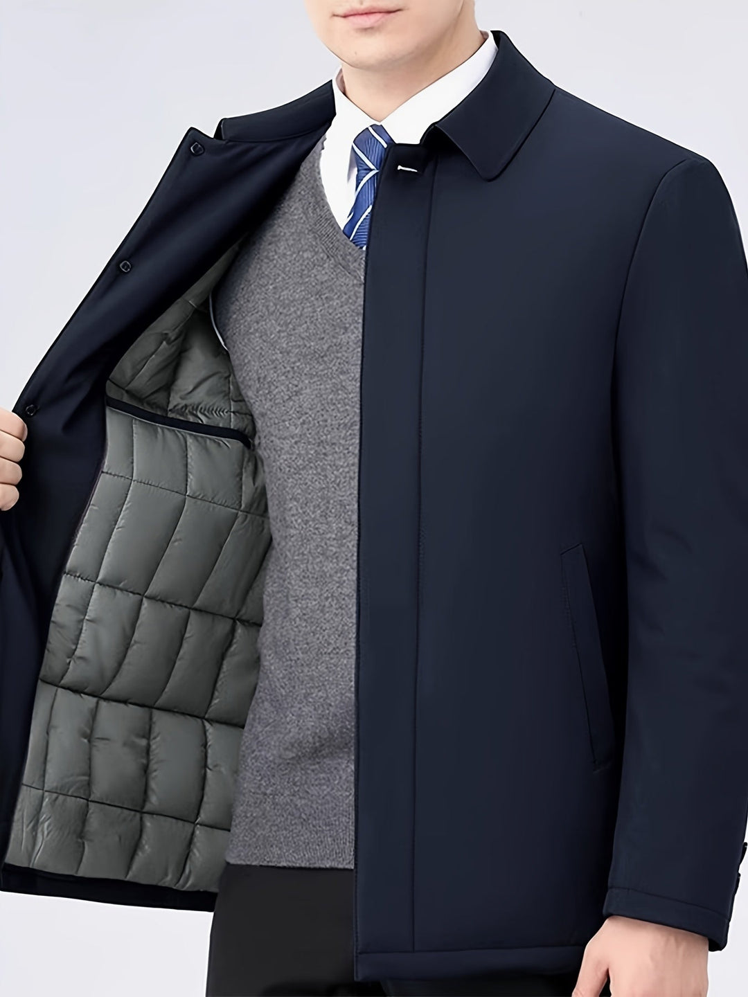 Mann in dunkelblauem Mantel mit grauem Pullover und Krawatte, Businessmode, Herrenbekleidung.