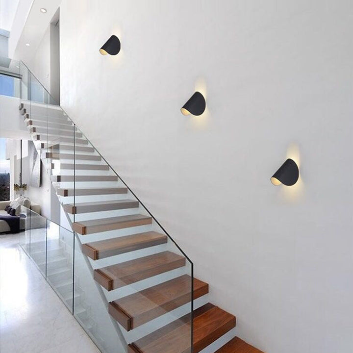 Moderne Treppenhausbeleuchtung, schwarze Wandlampen, minimalistisches Design, Holzstufen.