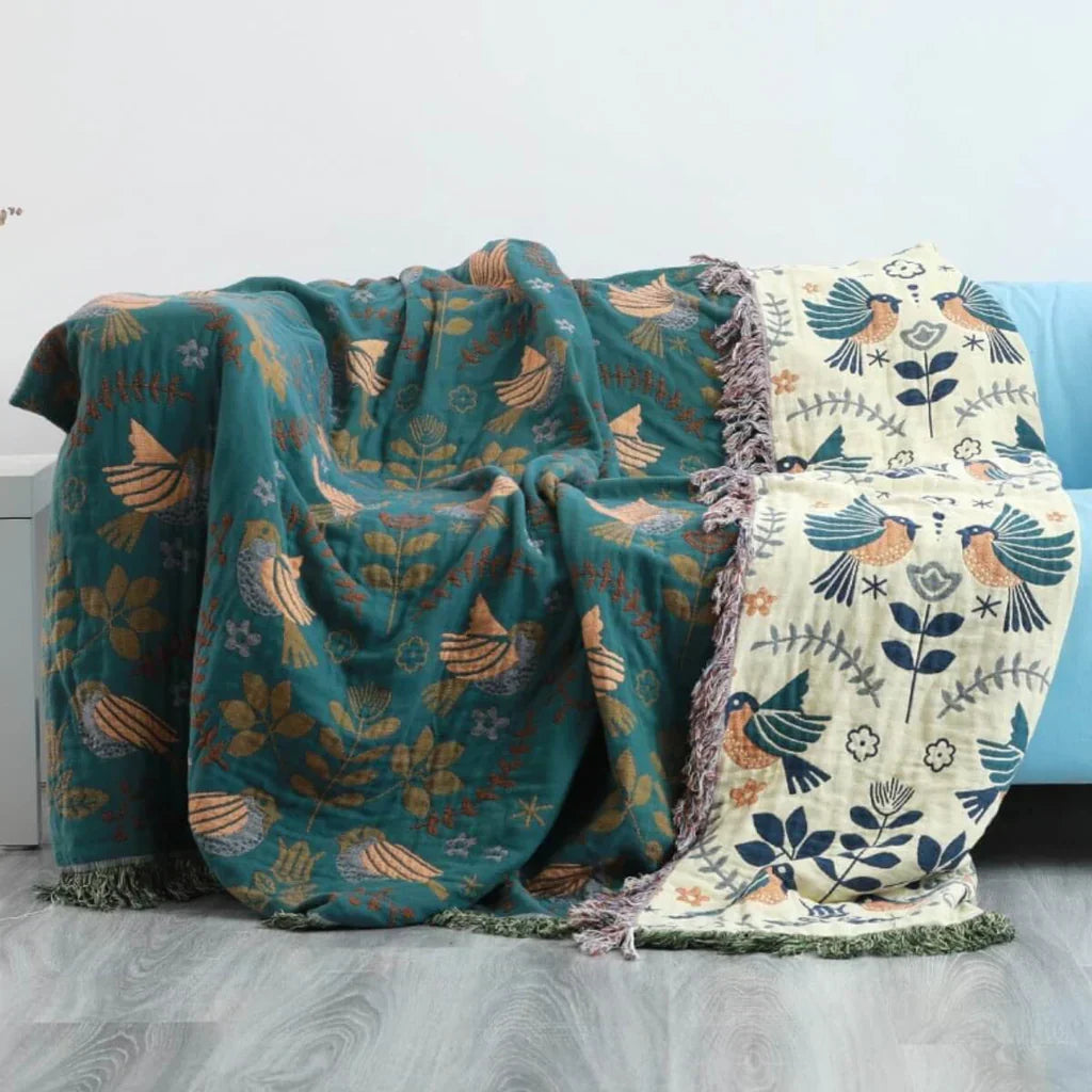 Zwei bunte Decken mit Vogel- und Blumenmuster auf Sofa, Baumwolle, Wohnzimmer-Dekoration.