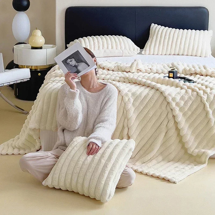 Weiche cremefarbene Kunstfell-Decke und Kissen auf Bett, gemütlich, Herbst Winter Wohnaccessoire.