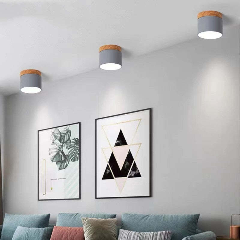 Moderne Deckenleuchten aus Holz und Metall in Wohnzimmer mit Wandkunst und Sofakissen.