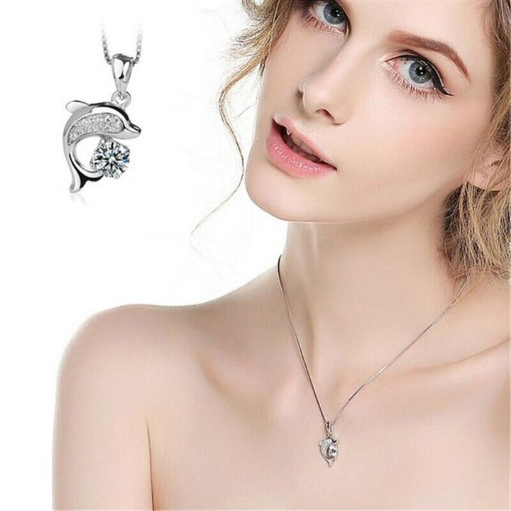 Frau mit silbernem Delfin-Anhänger, Zirkonia, eleganter Schmuck, modisches Accessoire.