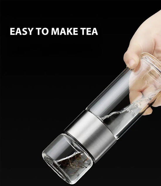 Hand hält transparenten Teebereiter aus Glas mit Edelstahlfilter, ideal für einfachen Teegenuss.