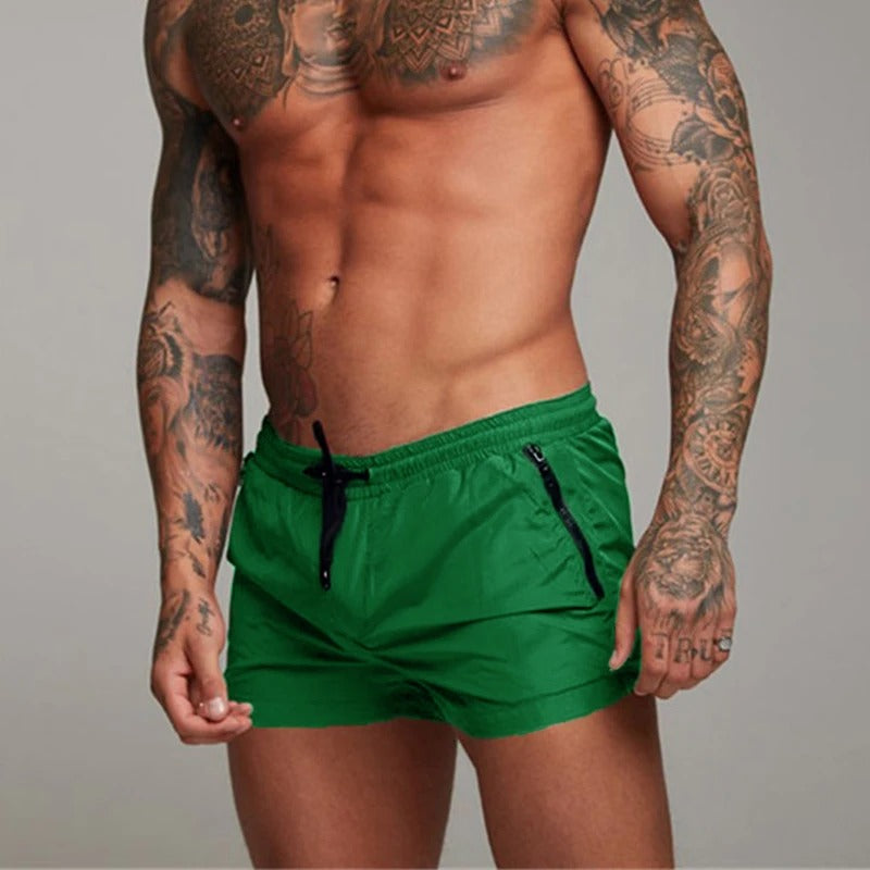 Mann in grüner Sportshorts, tätowiert, muskulös, Fitnessmode, Herrenbekleidung, Sportbekleidung.