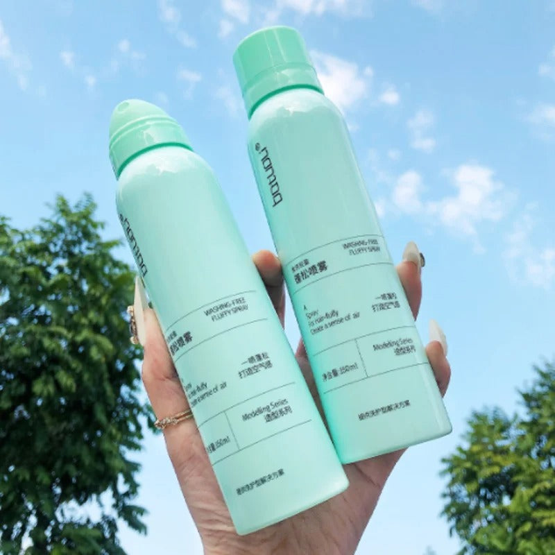 Zwei grüne Sprühflaschen, Hautpflege, 150ml, vor blauem Himmel und Bäumen.