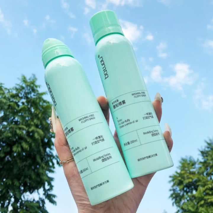 Zwei grüne Sprühflaschen, Hautpflege, 150ml, vor blauem Himmel und Bäumen.