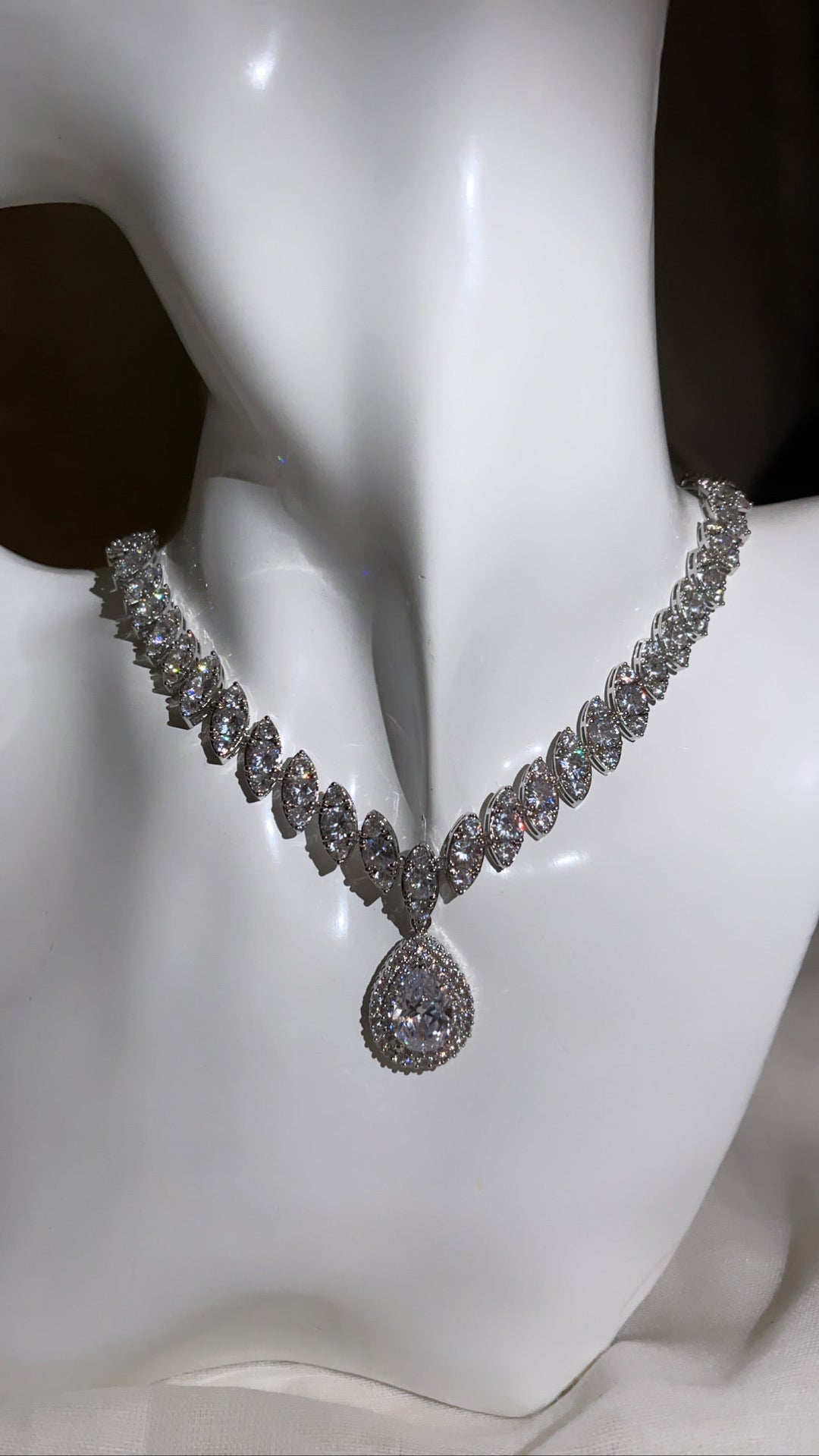 Luxuriöse Diamant-Halskette mit ovalen Steinen und rundem Anhänger auf weißem Hintergrund.