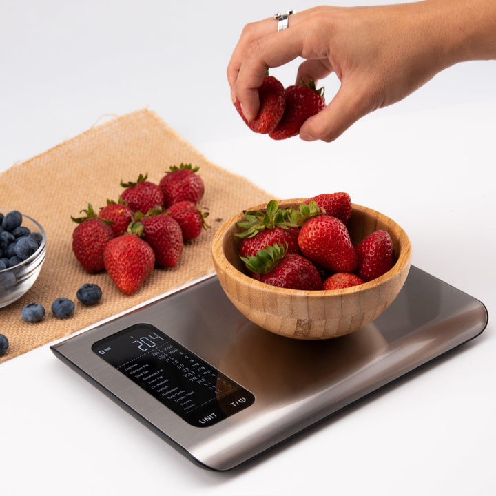 Digitale Küchenwaage aus Edelstahl mit Erdbeeren in Holzschale, moderne Lebensmittelwaage.