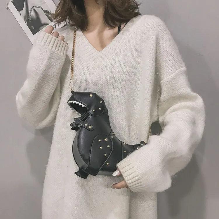 Frau mit schwarzer Dinosaurier-Handtasche, Nieten, Kettengurt, modisches Accessoire, weißer Pullover.